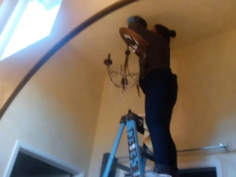 Electrician installing a chandelier in a Henderson residence
